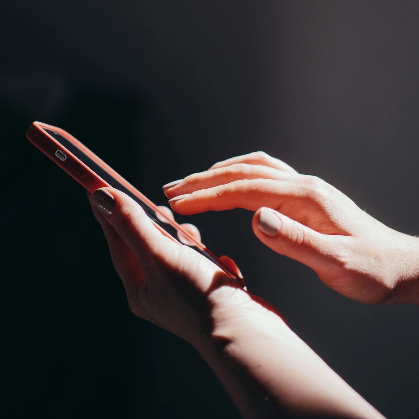 Hands interacting with a smartphone in a well-lit setting, emphasizing connection and technology.